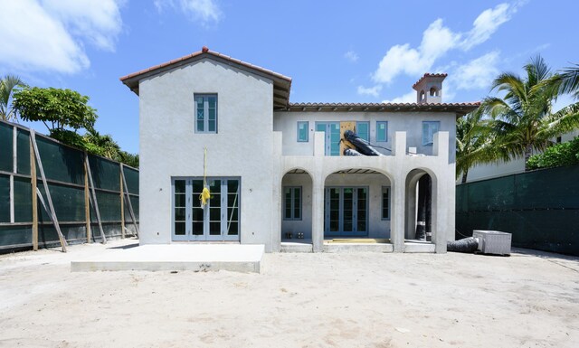 rear view of house with a patio, stucco siding, a tile roof, and fence