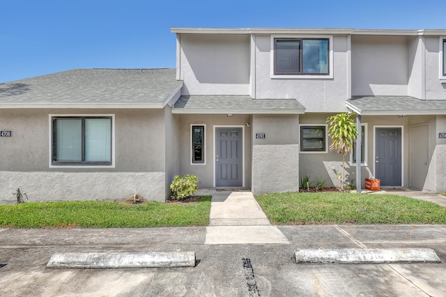 multi unit property with stucco siding and roof with shingles