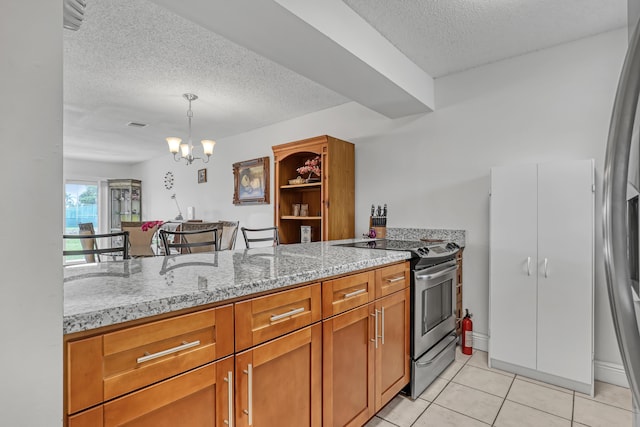 kitchen featuring a chandelier, light stone countertops, appliances with stainless steel finishes, brown cabinetry, and light tile patterned floors