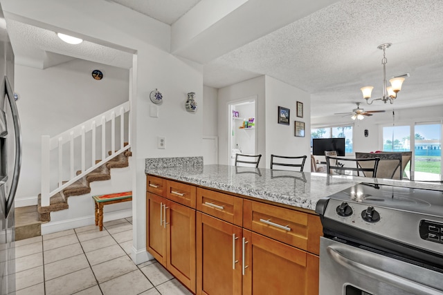 kitchen featuring light tile patterned flooring, light stone counters, a textured ceiling, brown cabinets, and stainless steel electric stove