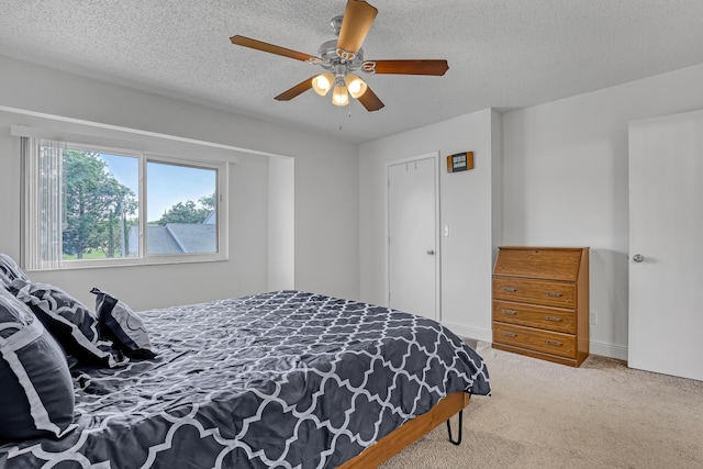 carpeted bedroom featuring a ceiling fan and a textured ceiling