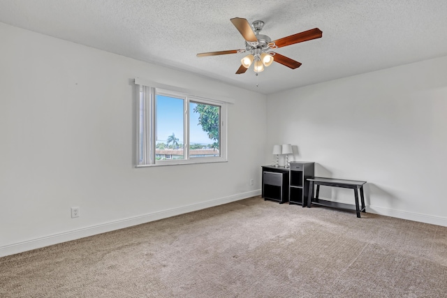 spare room featuring baseboards, carpet flooring, ceiling fan, and a textured ceiling