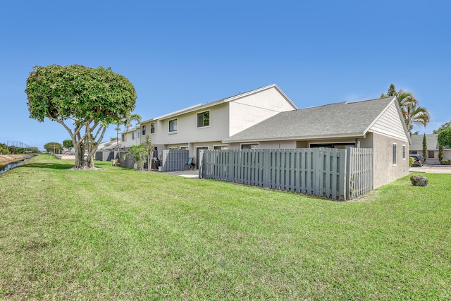 back of property featuring a yard and fence