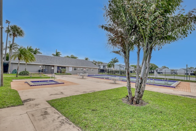 view of home's community featuring a lawn, fence, a swimming pool, and a patio area