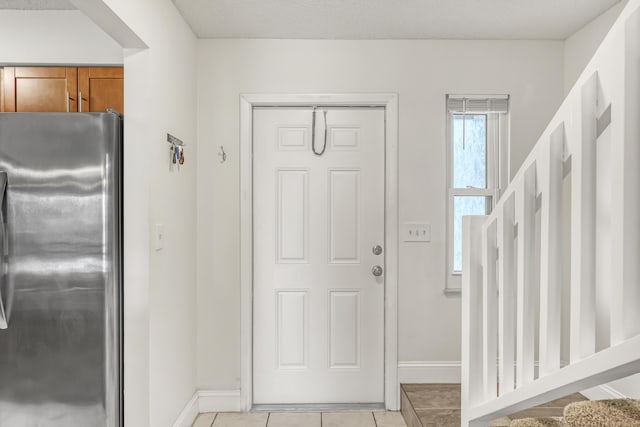 entryway featuring light tile patterned flooring, baseboards, and stairway