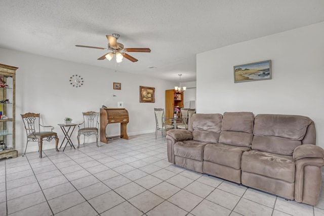 living room featuring light tile patterned floors, ceiling fan with notable chandelier, and a textured ceiling