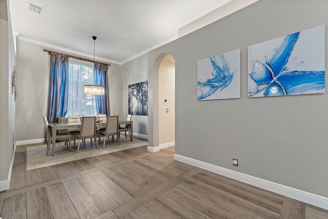 149 Sedona Way, Palm Beach Gardens, FL 33418 - dining area with arched walkways, crown molding, a chandelier, baseboards, and wood finished floors