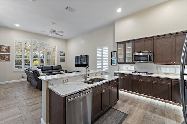 149 Sedona Way, Palm Beach Gardens, FL 33418 - kitchen with a sink, appliances with stainless steel finishes, a ceiling fan, an island with sink, and dark brown cabinetry