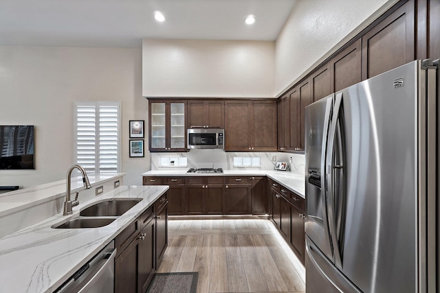 149 Sedona Way, Palm Beach Gardens, FL 33418 - kitchen featuring stainless steel appliances, a sink, dark brown cabinets, light stone counters, and light wood-style flooring