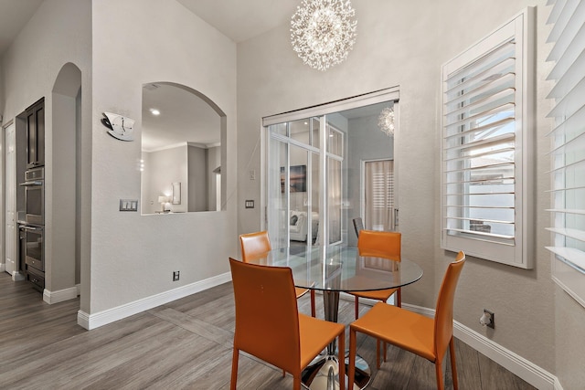 149 Sedona Way, Palm Beach Gardens, FL 33418 - dining room featuring arched walkways, baseboards, wood finished floors, and a chandelier