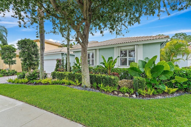 149 Sedona Way, Palm Beach Gardens, FL 33418 - view of front of property with an attached garage, a tiled roof, stucco siding, and a front lawn