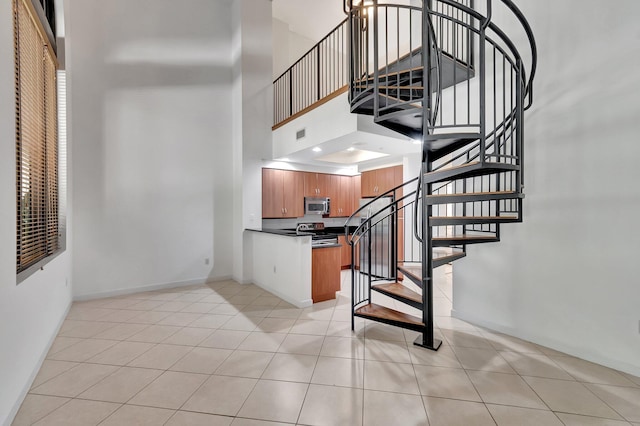 801 S Olive Ave Unit 127, West Palm Beach, FL 33401 - stairway featuring baseboards, visible vents, tile patterned floors, and a high ceiling
