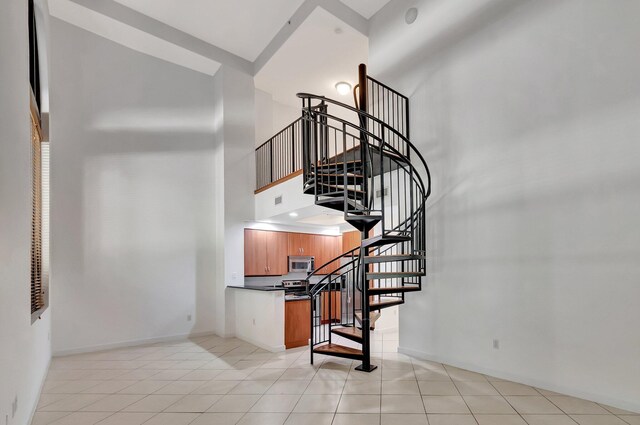 801 S Olive Ave Unit 127, West Palm Beach, FL 33401 - stairs with a towering ceiling, tile patterned floors, and baseboards