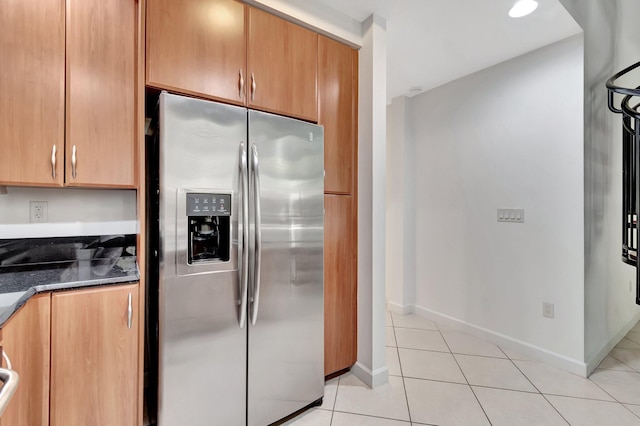 801 S Olive Ave Unit 127, West Palm Beach, FL 33401 - kitchen featuring dark stone counters, light tile patterned flooring, baseboards, and stainless steel fridge with ice dispenser