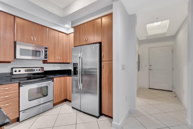 801 S Olive Ave Unit 127, West Palm Beach, FL 33401 - kitchen featuring appliances with stainless steel finishes, light tile patterned floors, dark countertops, and baseboards