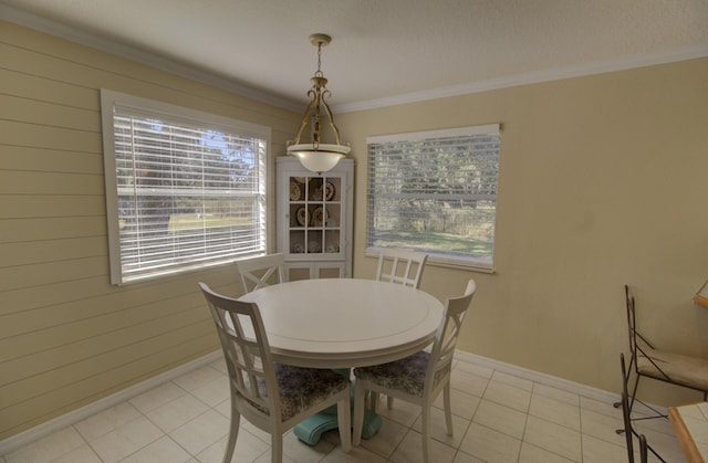 dining room with light tile patterned floors, baseboards, and crown molding