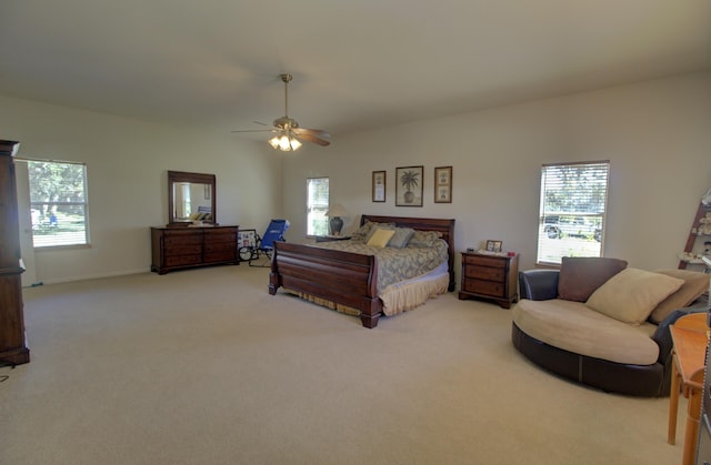 bedroom with light colored carpet, multiple windows, and a ceiling fan