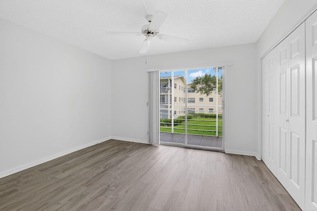 63 Dorset Unit B, Boca Raton, FL 33434 - unfurnished bedroom with wood finished floors, multiple windows, a closet, access to outside, and a textured ceiling