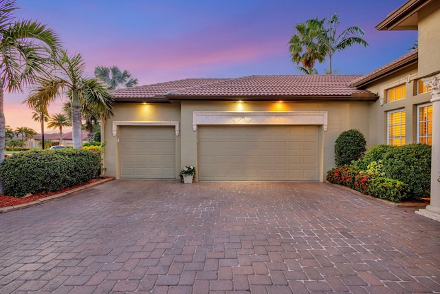 garage at dusk featuring decorative driveway