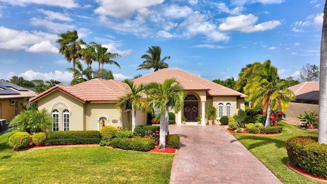 mediterranean / spanish home with a tiled roof, decorative driveway, stucco siding, and a front lawn