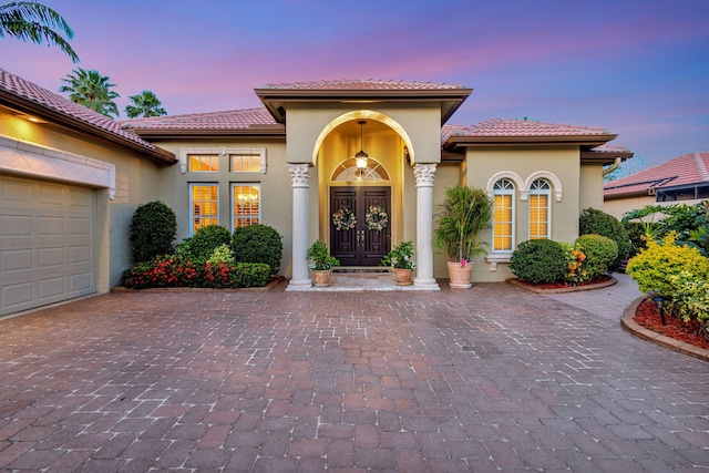 entrance to property with french doors, a tiled roof, and stucco siding