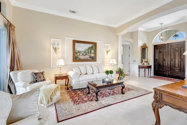 living area with tile patterned floors, visible vents, arched walkways, and ornamental molding