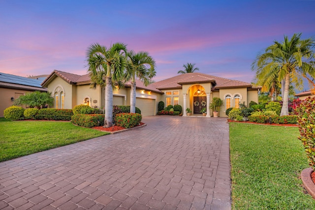 mediterranean / spanish-style home featuring stucco siding, a tile roof, and decorative driveway