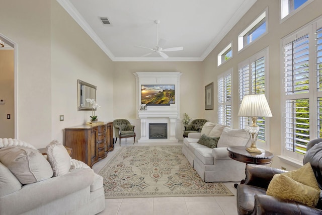 living area featuring light tile patterned flooring, a wealth of natural light, crown molding, visible vents, and ceiling fan