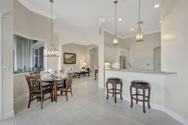 kitchen with visible vents, light stone countertops, a kitchen bar, arched walkways, and freestanding refrigerator