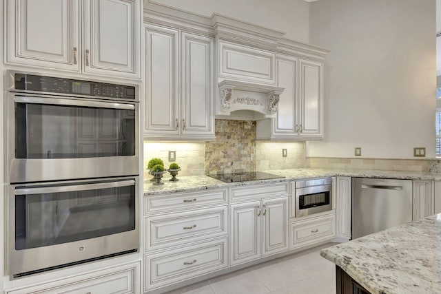 kitchen featuring light stone counters, backsplash, appliances with stainless steel finishes, light tile patterned floors, and white cabinets
