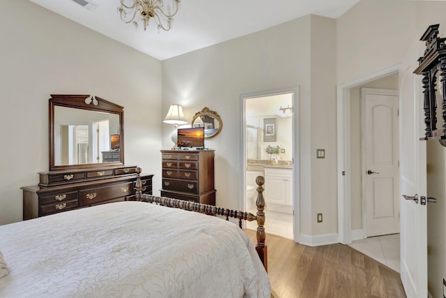 bedroom featuring baseboards, ensuite bath, a chandelier, and light wood-type flooring