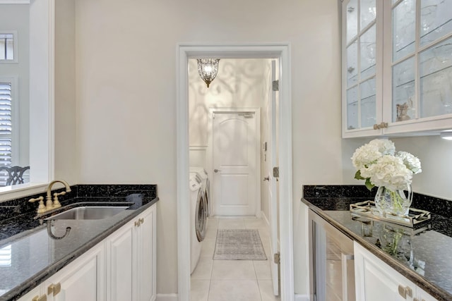 clothes washing area with wine cooler, a sink, separate washer and dryer, laundry area, and light tile patterned floors
