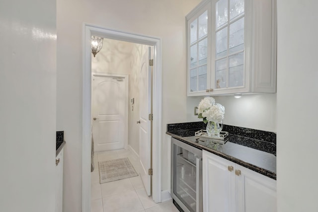 kitchen featuring dark stone counters, light tile patterned flooring, white cabinetry, and wine cooler