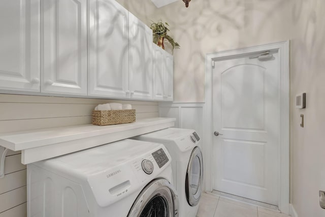 laundry area with washer and clothes dryer, wainscoting, cabinet space, and light tile patterned floors