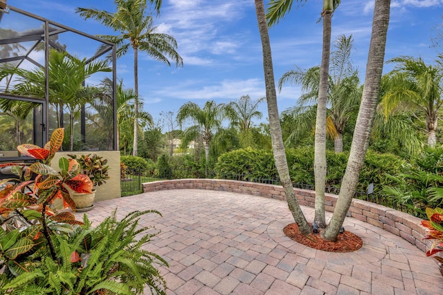 view of patio featuring glass enclosure and fence