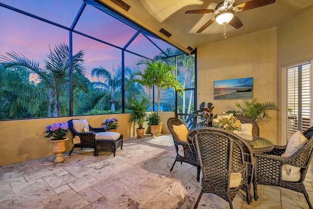 patio terrace at dusk featuring glass enclosure and ceiling fan