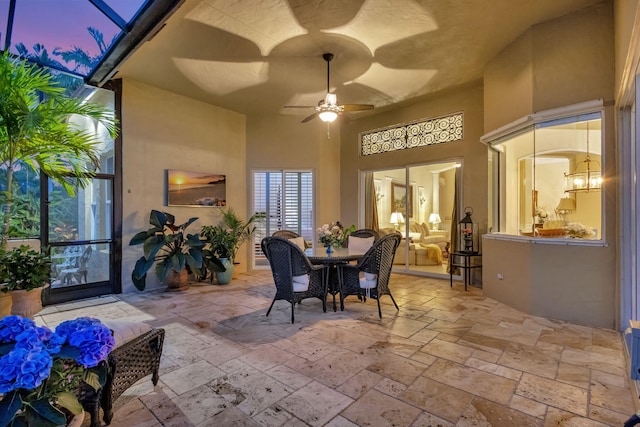 view of patio with a ceiling fan, outdoor dining space, and a lanai