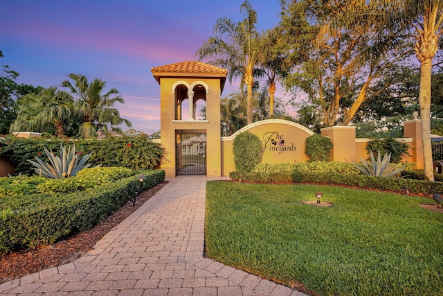 community / neighborhood sign featuring a gate and a yard