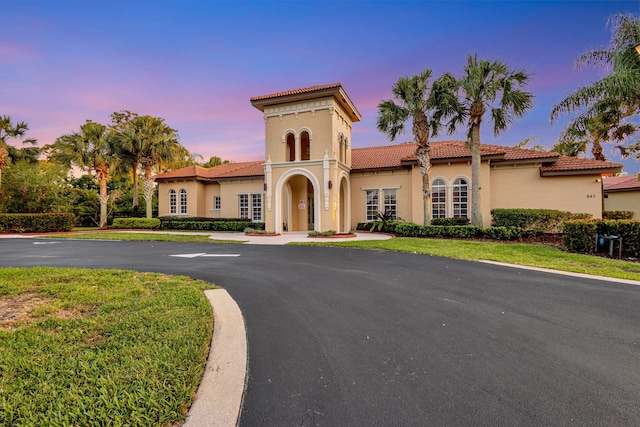 view of front of property with a tile roof, stucco siding, and a yard