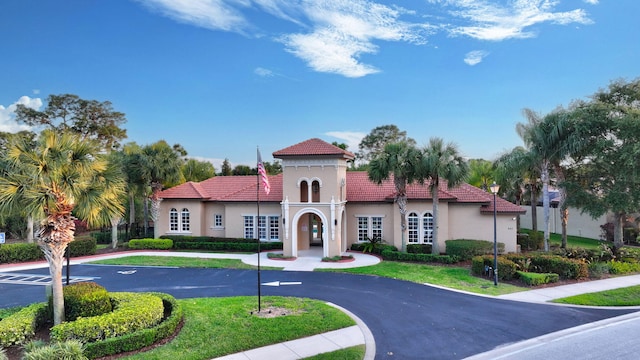 mediterranean / spanish-style house with uncovered parking, a front yard, stucco siding, and a tiled roof