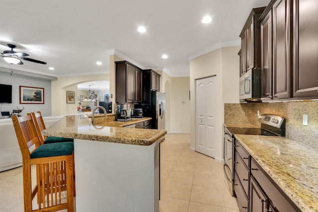 9328 Silent Oak Cir, West Palm Beach, FL 33411 - kitchen featuring ceiling fan, a kitchen breakfast bar, arched walkways, dark brown cabinets, and appliances with stainless steel finishes