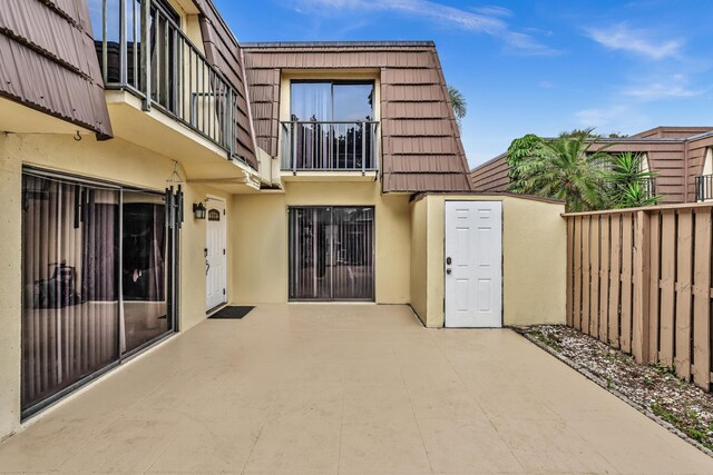 211 2nd Ct, Palm Beach Gardens, FL 33410 - back of house with stucco siding, mansard roof, a patio area, a tile roof, and a balcony