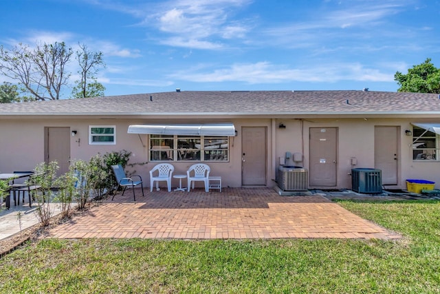 1245 High Point Pl S Unit C, Delray Beach, FL 33445 - back of property featuring central air condition unit, a patio, stucco siding, and roof with shingles