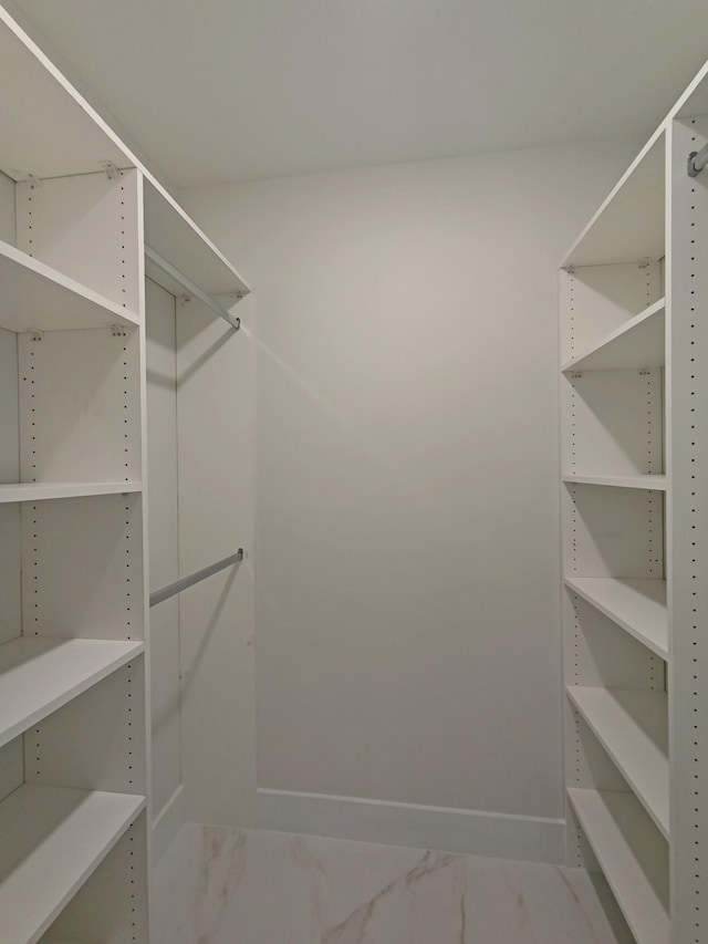 walk in closet featuring marble finish floor