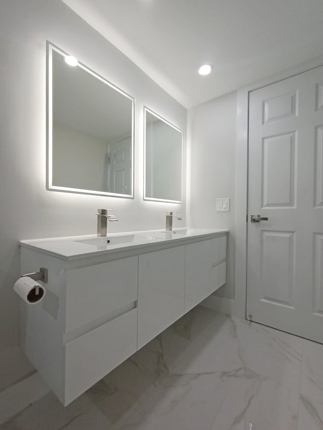 full bath with a sink, marble finish floor, double vanity, baseboards, and recessed lighting