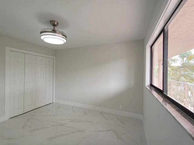 unfurnished bedroom featuring baseboards, marble finish floor, and a closet