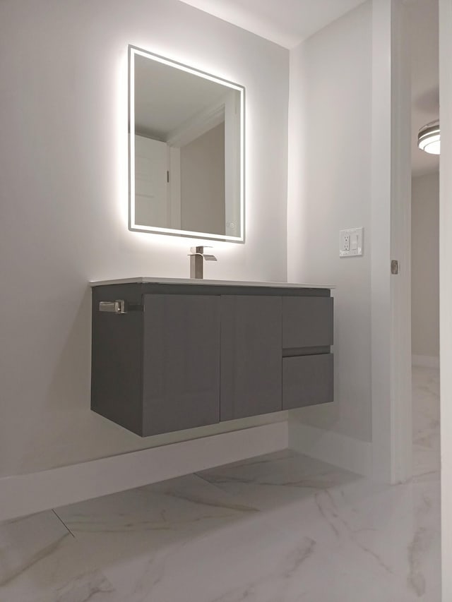 bathroom with marble finish floor, baseboards, and vanity