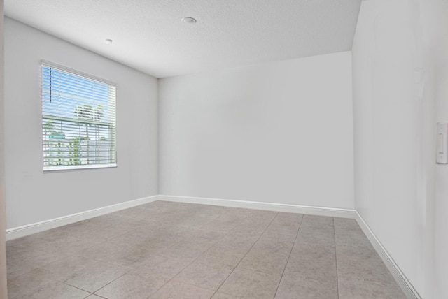 spare room with baseboards and a textured ceiling