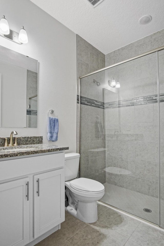 full bath featuring tile patterned flooring, vanity, toilet, a textured ceiling, and a shower stall