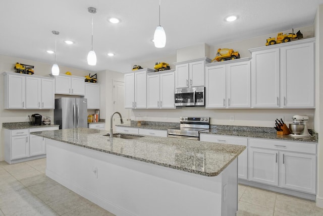 kitchen with light tile patterned floors, a sink, white cabinets, a kitchen island with sink, and appliances with stainless steel finishes